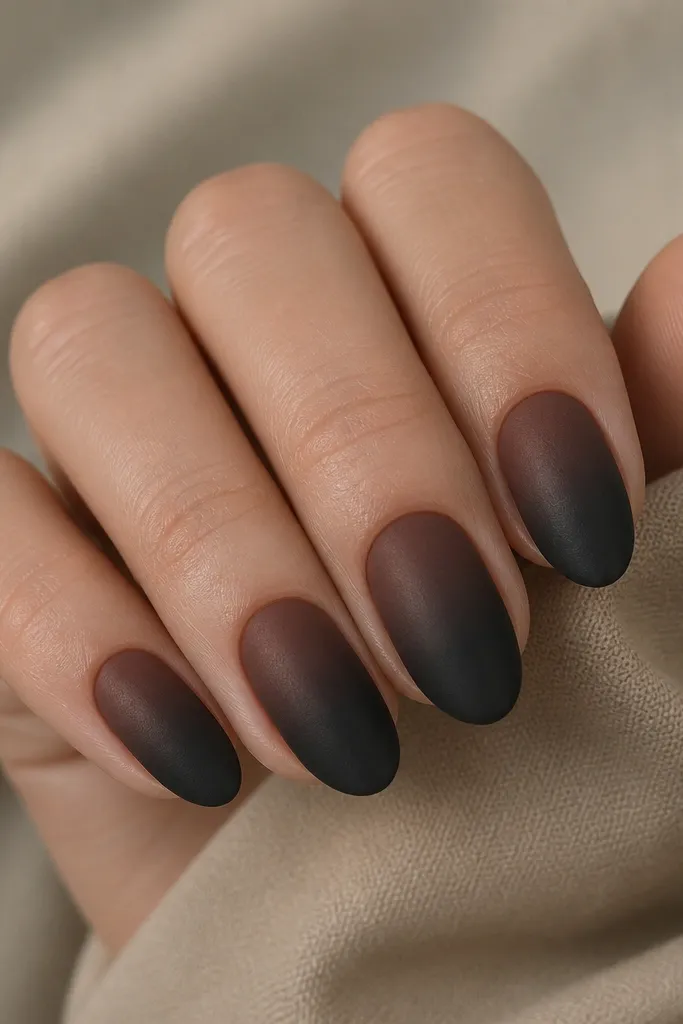 Short almond nails with a gradient from warm chocolate brown near the cuticle fading into matte black at the tips. The blend is smooth, and the black tips are clearly matte.