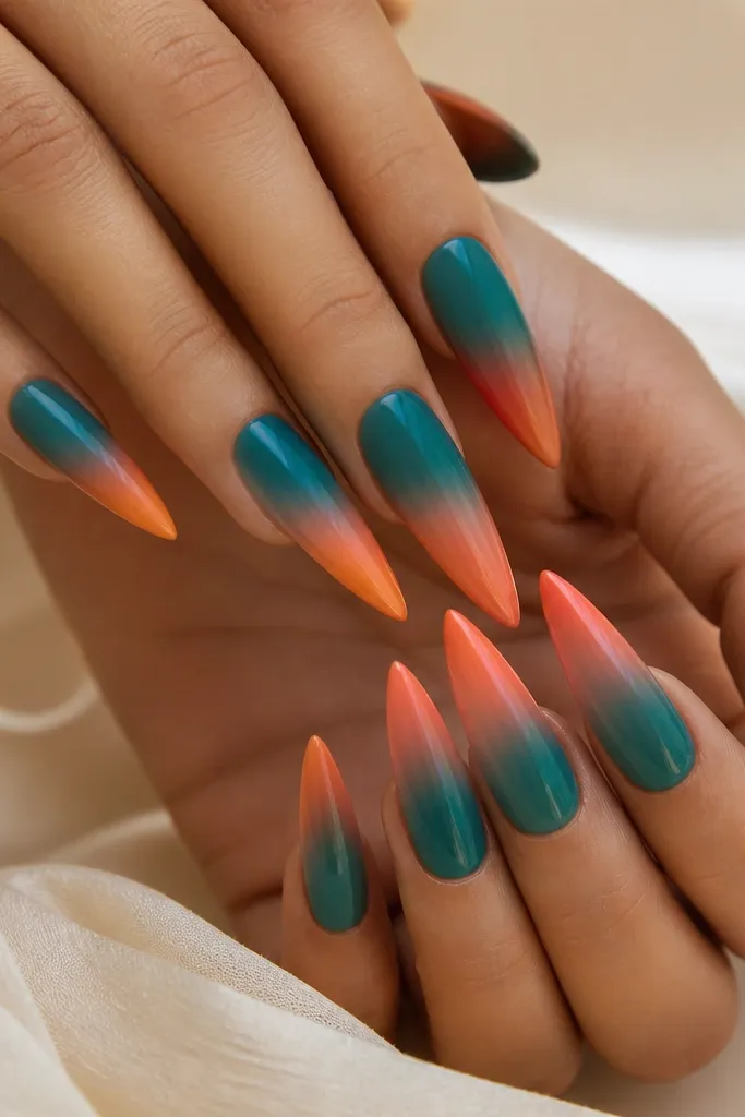 Stiletto nails with a teal-blue base fading into a hot coral-orange ombre at the tips. The transition looks smooth like a sky with a horizon line.
