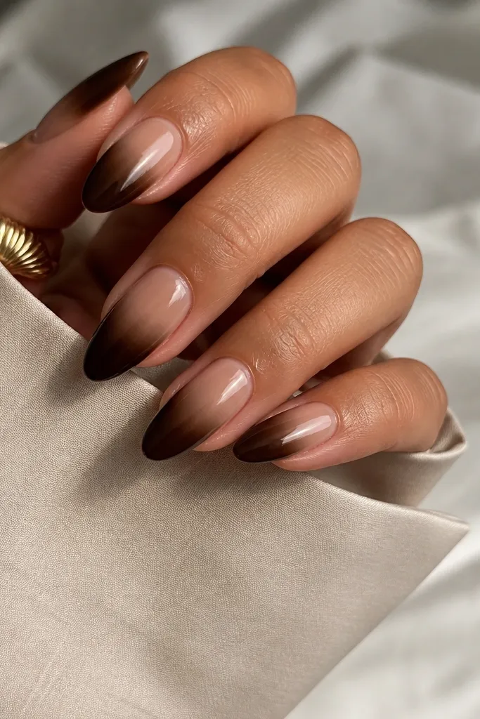 Almond nails with a nude beige base fading into an espresso brown at the tips; the contrast is stronger than typical nudes and the finish is high gloss.