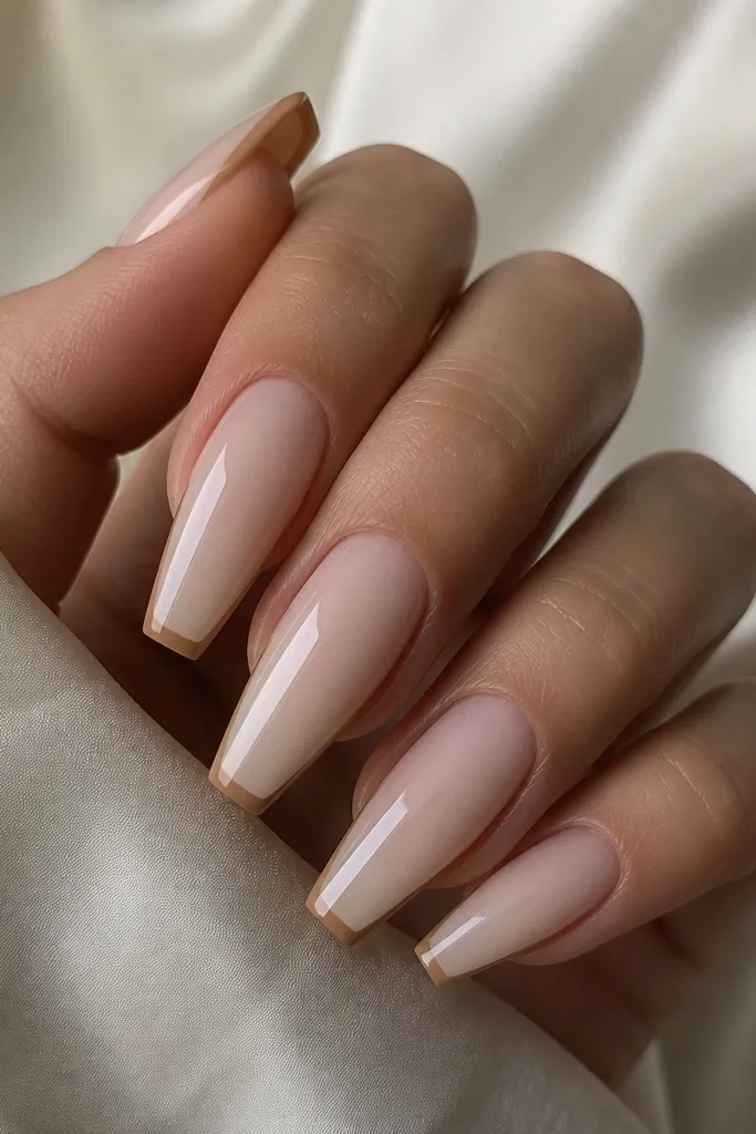 A set of coffin nails with a milky nude base. The French tips are thin and straight, painted in light warm brown like latte foam. The line is crisp with no smudging, and the top coat is glossy.