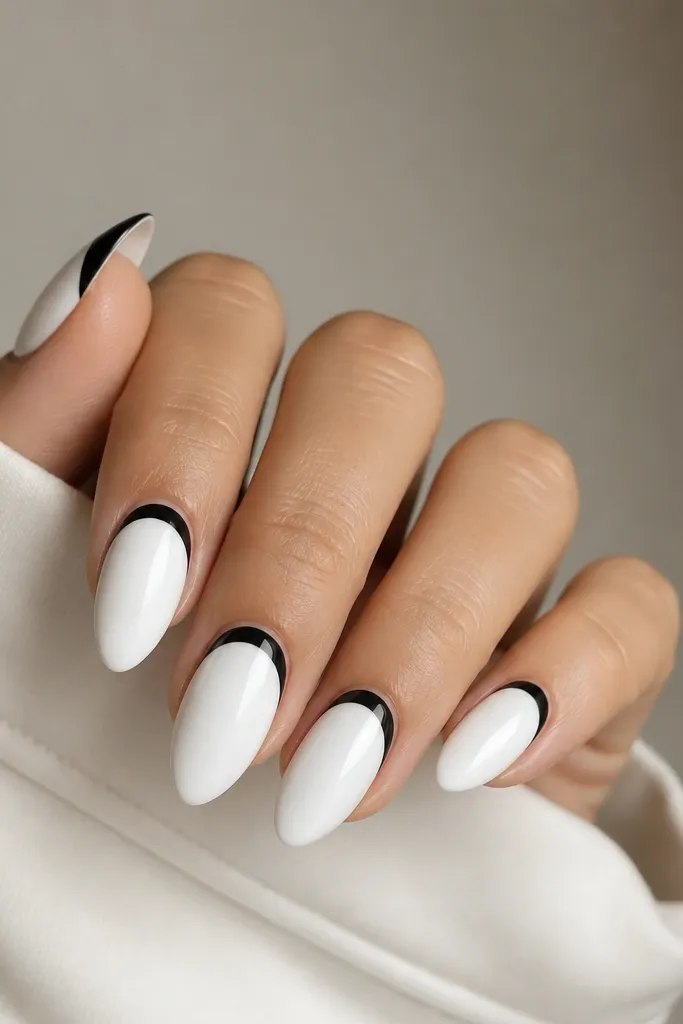 Five white almond nails with a clean black half-moon at the tip area. The black forms a smooth arc across each nail, leaving a bright white center and crisp cuticle edge.