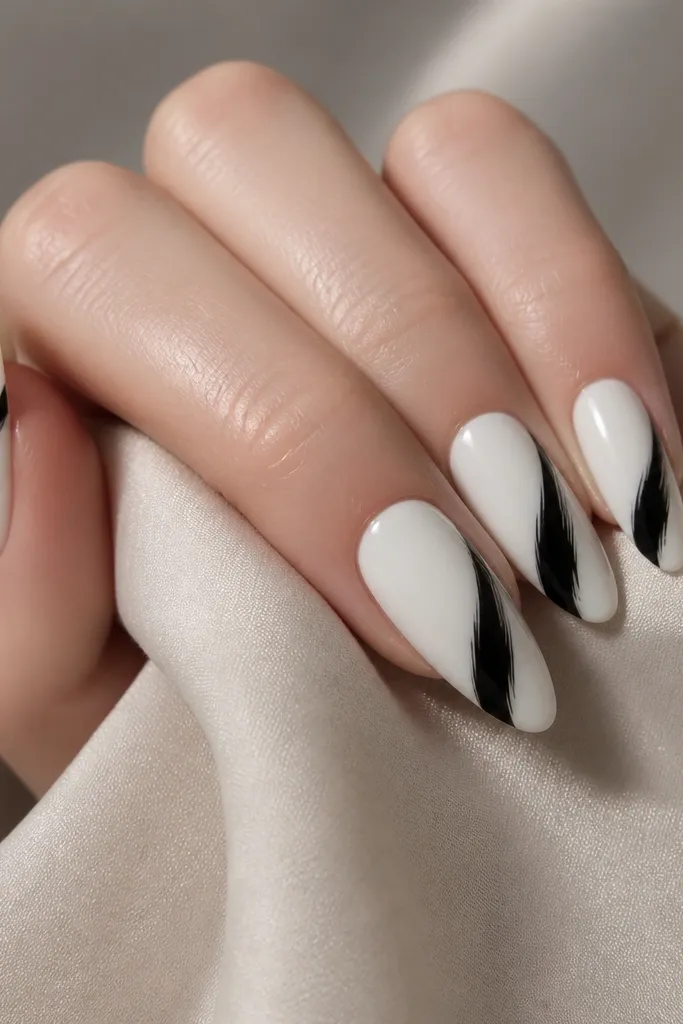 White almond nails with one bold black swoop across each nail. The swoop has a tapered end and a slightly feathered edge, but it stays clean and controlled.