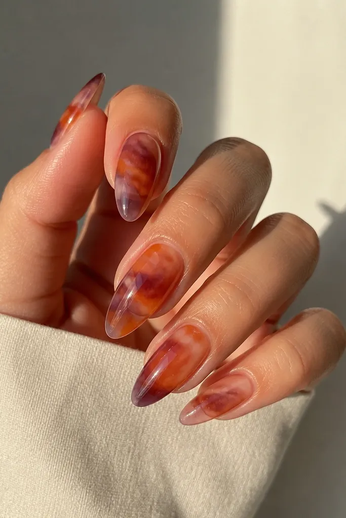 A see-through, glossy sunset effect: clear base with layered orange wisps and a plum tint near the tip, giving a liquid-glass look.