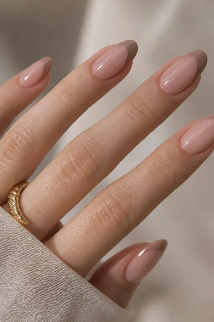 Almond nails with a sheer rosy base. The French tips are neutral taupe-brown, slightly softer at the inner edge, with a glossy shine.