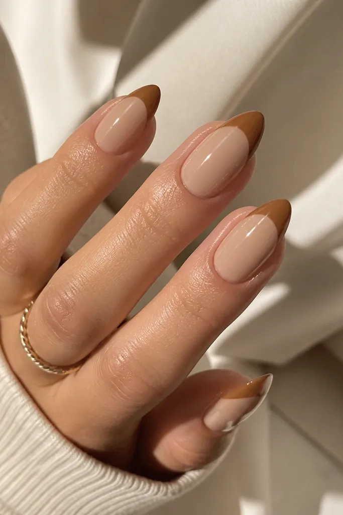 Almond nails with a warm beige base. French tips are caramel brown with a smooth, rounded smile line and a high shine top coat.