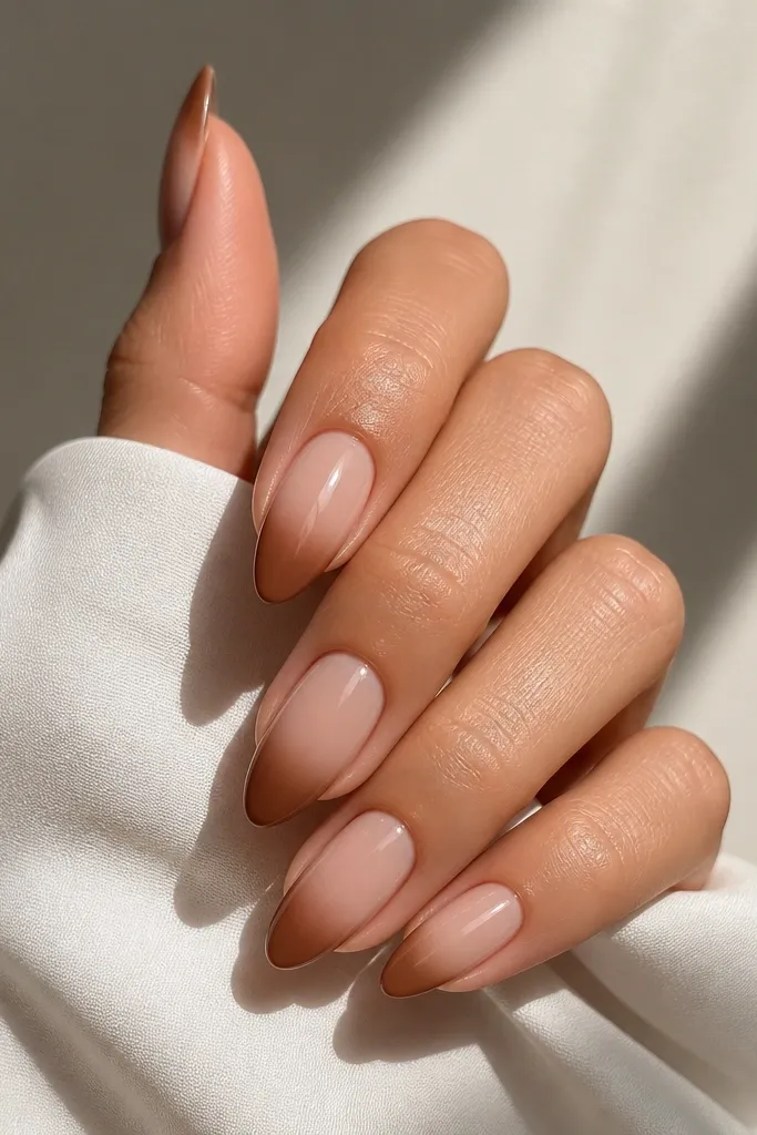 Almond nails with a nude base. The French tip starts as mocha brown at the outer edge and fades lighter toward the inner edge, with a glossy finish.