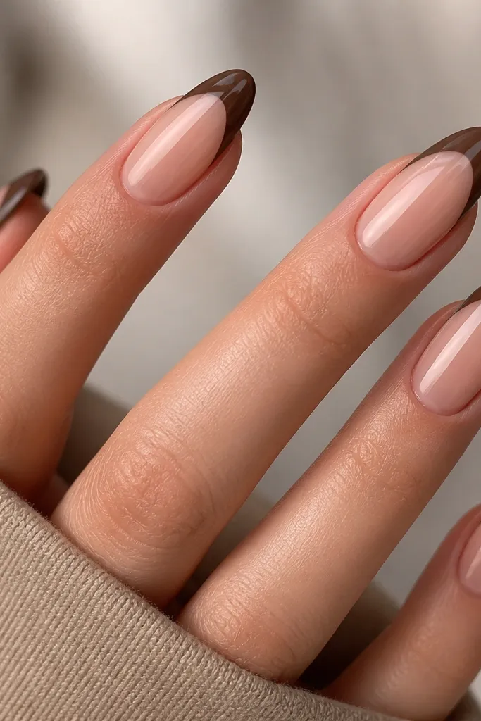 Four almond nails. The french tips are matte chocolate brown. Down the center of each tip is a single glossy stripe that reflects light like a highlight.