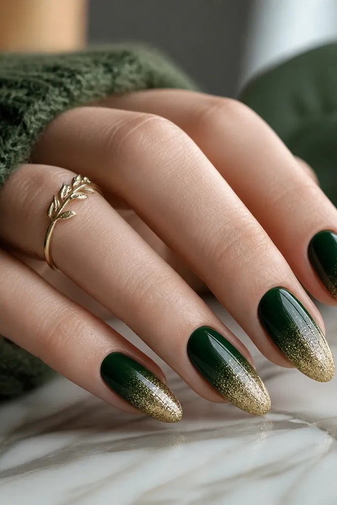 Medium almond nails with a smooth gradient: forest green deepens toward the cuticle and fades into gold glitter at the tips.