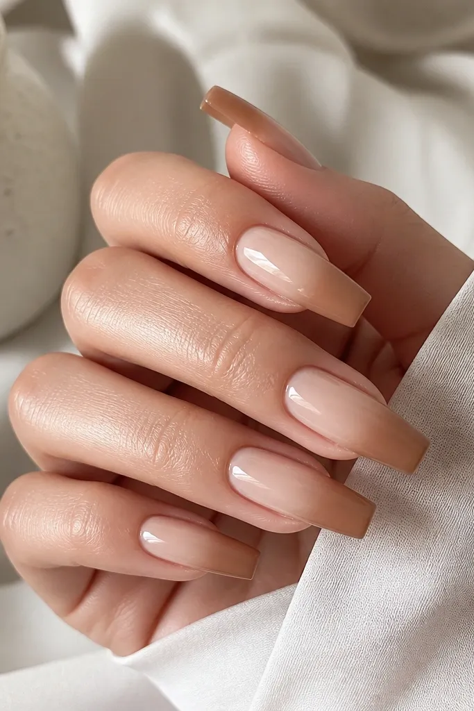 Long square nails with a smooth nude-to-warm-latte ombre. The base is creamy nude and the tips fade into a light brown latte tone, glossy finish.