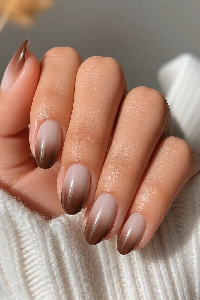 Short almond nails with a smooth gradient. The cuticle area is milky cream, and the rest of the nail fades into cocoa brown toward the tip. The gradient looks smooth, not streaky, with a glossy finish.