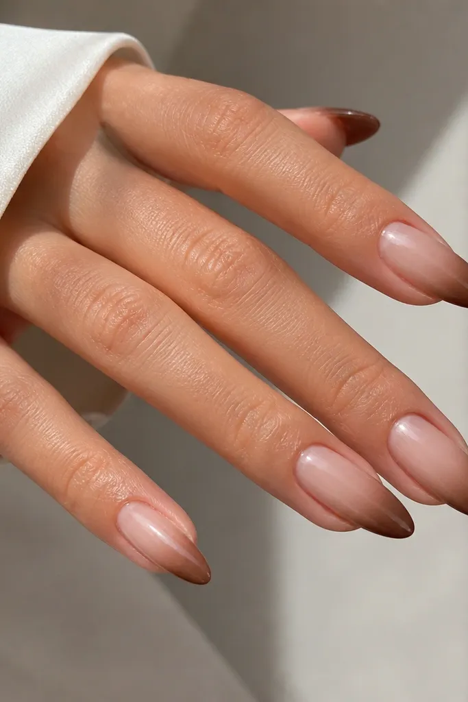 Almond nails with a sheer nude base fading into a brown tip. The brown is denser at the very edge and fades toward the center, glossy finish.