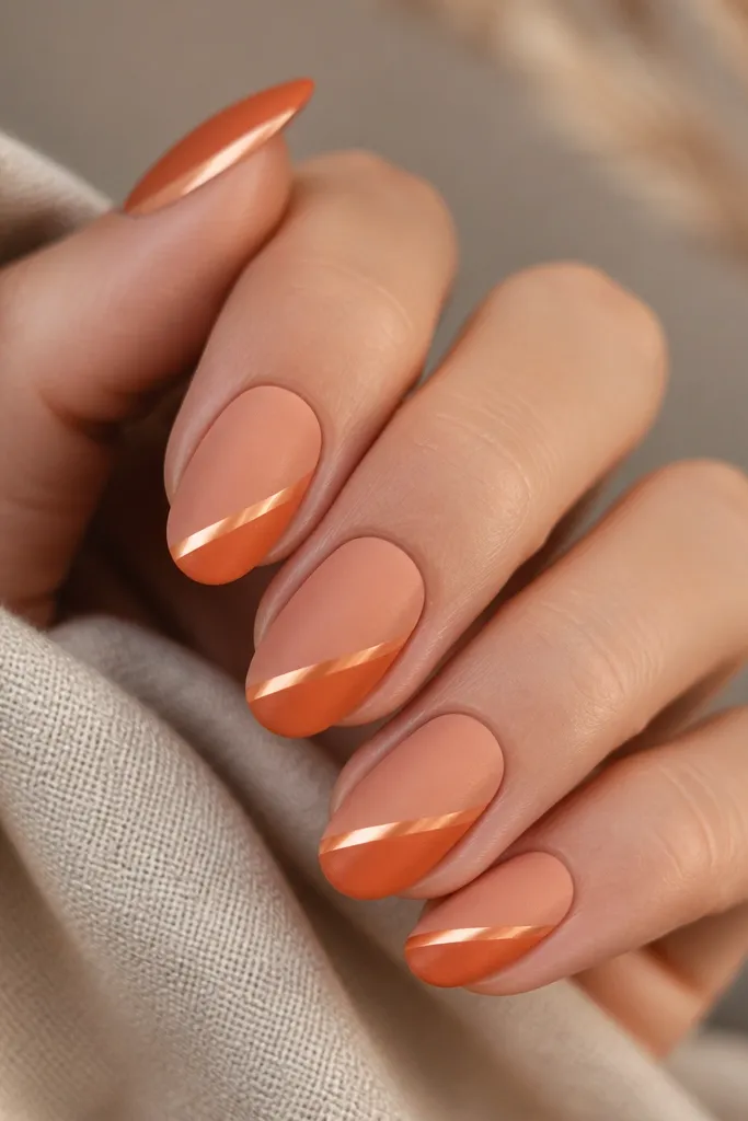 Matte finish nails in dusty peach and muted orange gradient. One glossy stripe runs diagonally near the tip, reflecting light like a sunbeam.