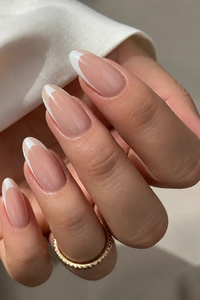 Almond nails with a sheer nude base. Milk white is painted only on the side edges near the tip, leaving the center nude and glossy.