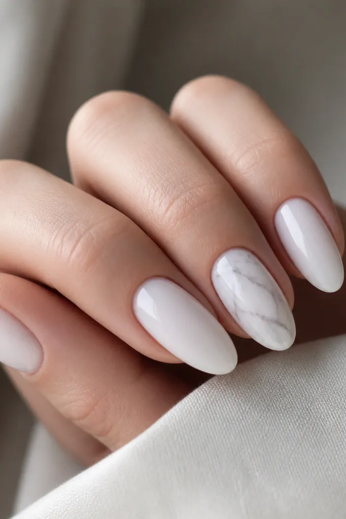 Milky white almond nails where one accent nail has thin grayish-white marble veins branching from the center. Glossy finish.