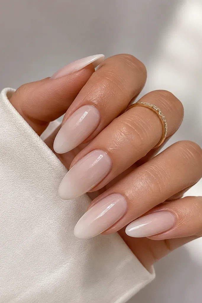 Almond nails with a sheer nude base and milky white applied as a translucent overlay on the upper half. The overlay fades slightly toward the center, making depth. Glossy finish.