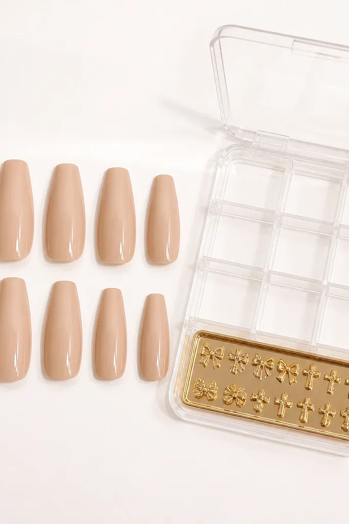 Ten nude coffin nails on a white background, glossy warm beige. A clear plastic storage case sits beside them with small divider slots and a mini gold charm tray.