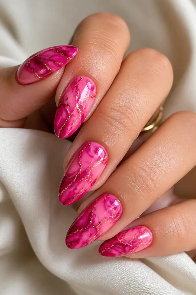 Medium almond nails featuring a swirling magenta and warm pink gradient. Thin gold lines trace the swirl like cracks in glass. High-gloss finish.