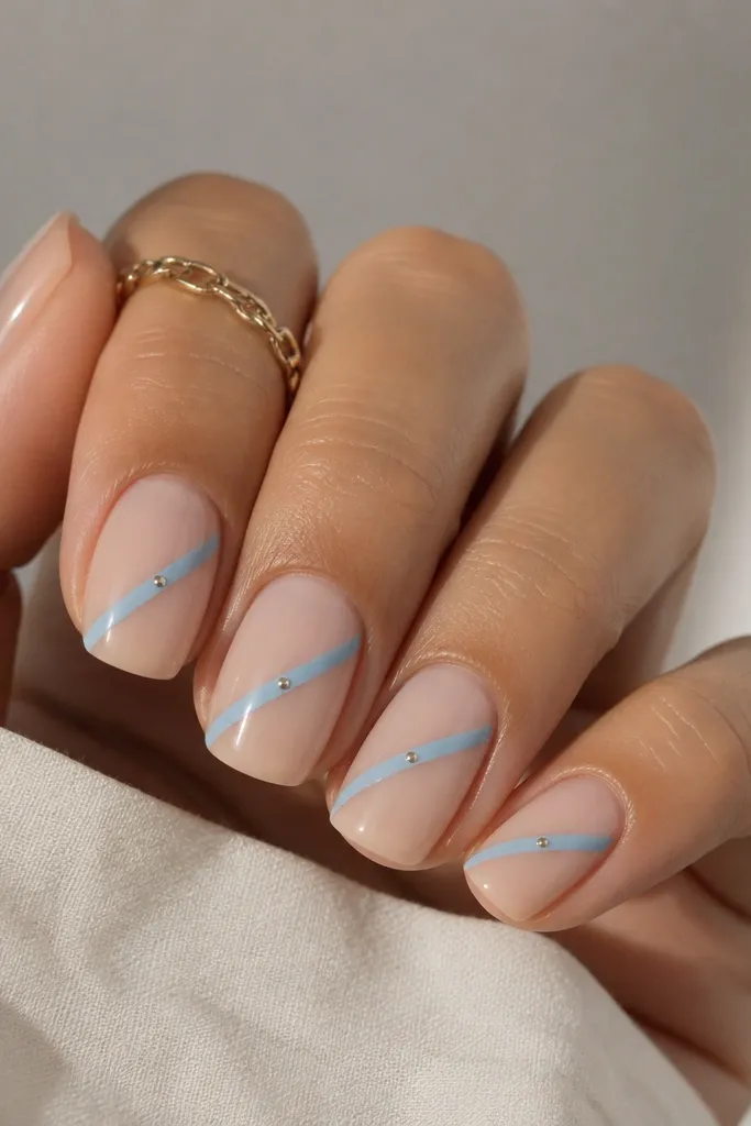 Short squoval nails with a sheer nude base. One diagonal sky blue stripe runs from the lower left near the cuticle to the upper right near the free edge, with a tiny silver dot at the center.