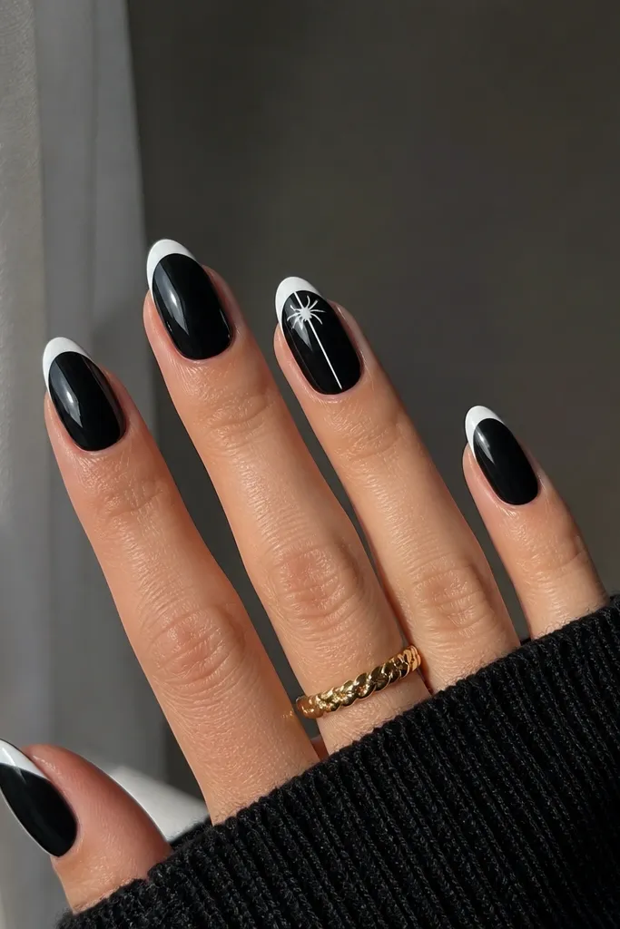 Base is glossy black. Tips are painted a crisp white French tip. On the ring finger, a thin white spider line goes from the tip down about halfway, with tiny dot legs at the top.