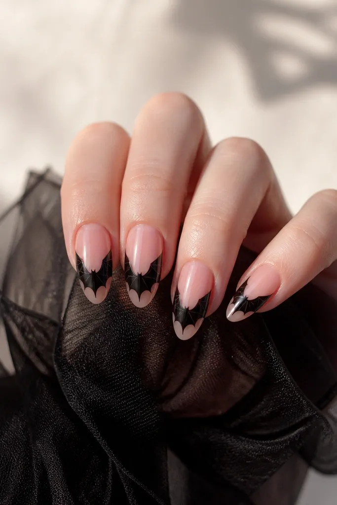 Sheer pink nails with black bat wing shapes drawn on the side of the nail, like wings spreading from the center to both edges.