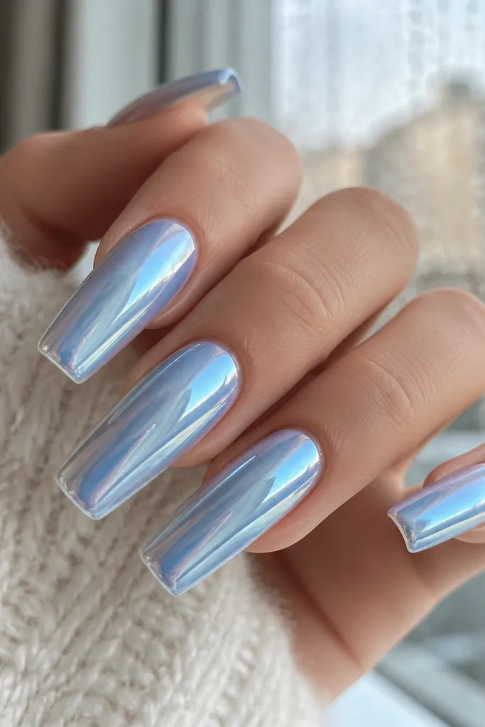 Long square acrylic nails with a clear jelly base. Over it, an icy sky-blue chrome powder creates a metallic, mirror-like sheen. The nails reflect light like a wet winter window.
