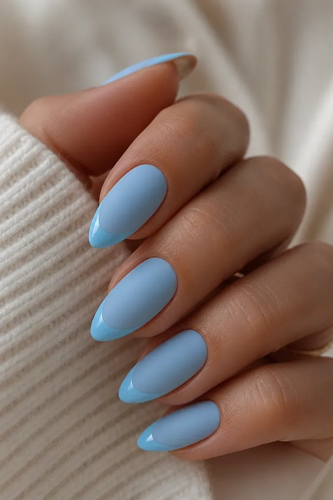 Almond nails with sky blue velvet matte finish on most of the nail. The tip has a thin glossy sky-blue French line that looks shiny against the matte. The contrast is crisp and clean.