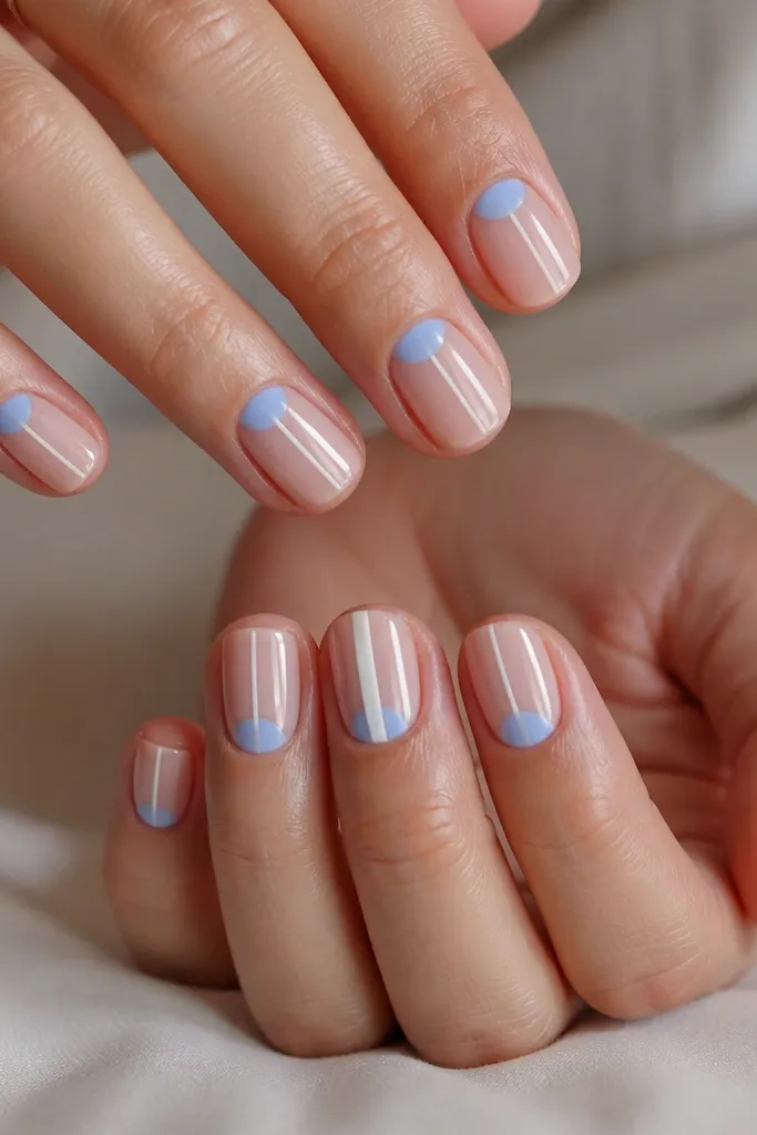 Short square nails with a cornflower sky blue half-moon at the cuticle on each nail, crisp white center line running from cuticle to near the tip, and a glossy clear top coat. One ring finger has a slightly thicker white line.