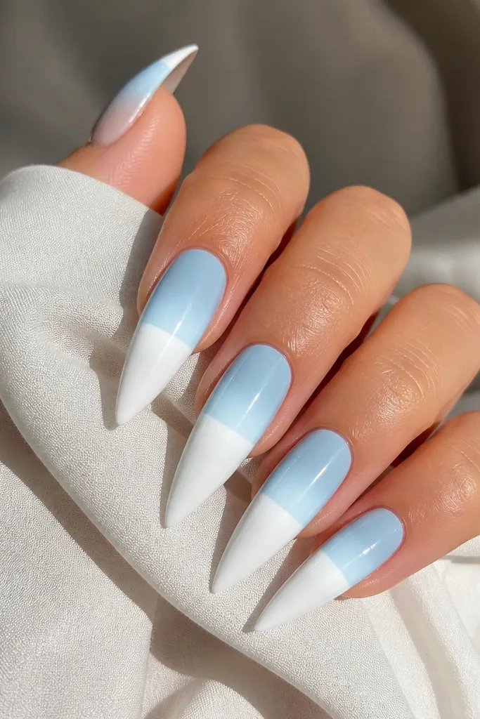 Long stiletto nails with sky blue ombré from near cuticle to mid-nail, then a crisp white sunrise line across the nail like a horizon. The gradient is smooth with glossy finish.
