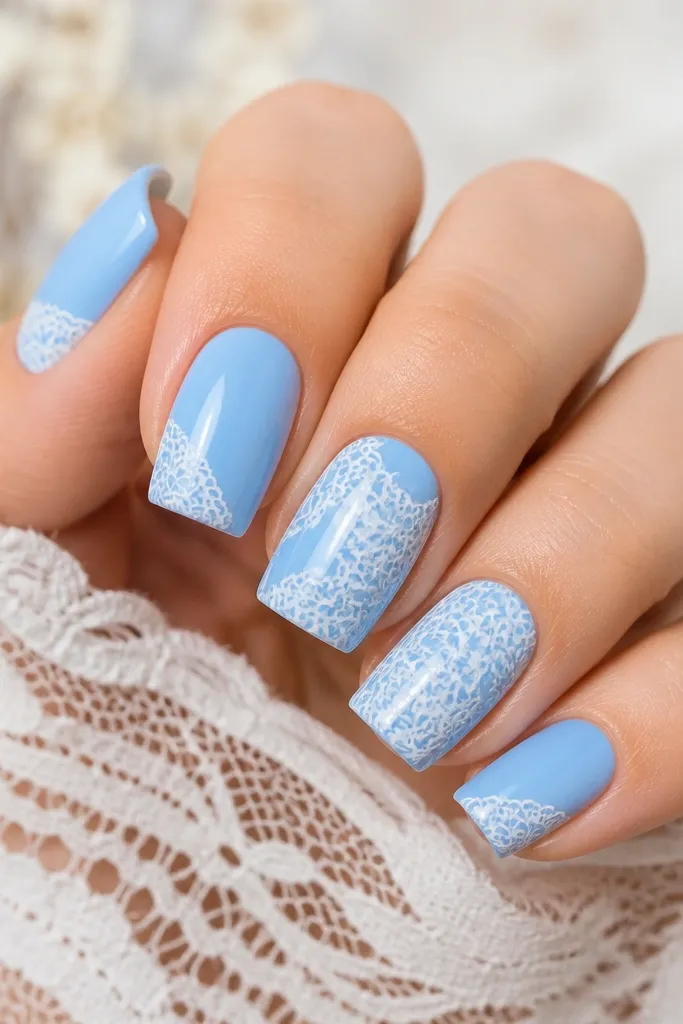 Medium square nails with glossy sky blue base. A white lace pattern is stamped on two middle nails and repeated in smaller sections on others. Clean, sharp stamp edges, crisp white lines.