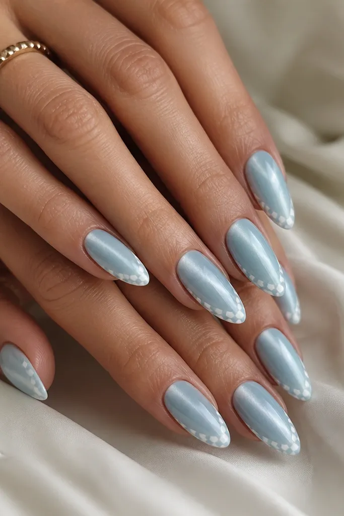 Almond nails with a baby blue cat eye stripe and a thin checker pattern along the outer edge in white and light blue.