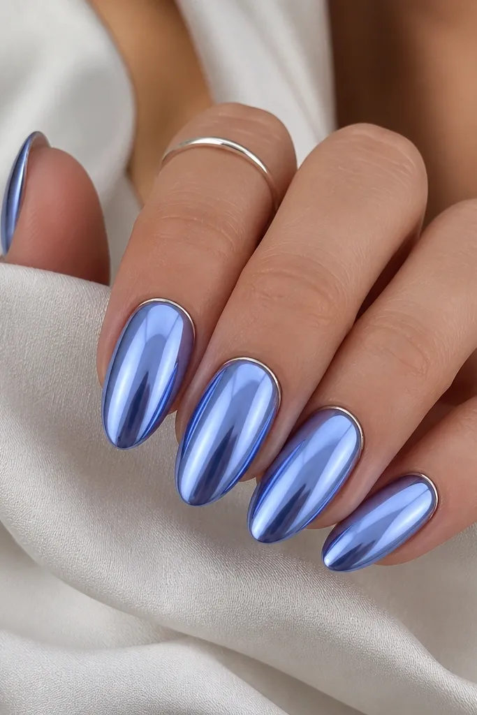 Medium almond nails with periwinkle sky chrome. A thin silver halo sits just above the cuticle line on each nail, leaving a tiny periwinkle gap around the edges. The rest of the nail is mirror shiny.