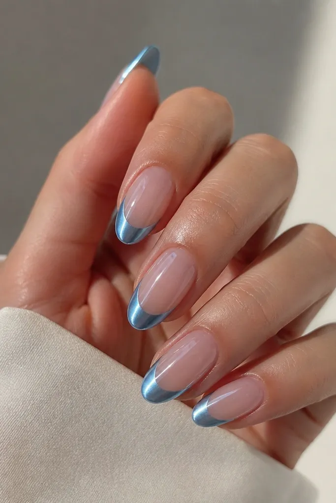 Medium almond nails with a clear jelly-looking base. The tips are baby blue chrome in a clean curved French shape. The shine is mirror on the tips only, while the base stays glassy and see-through.