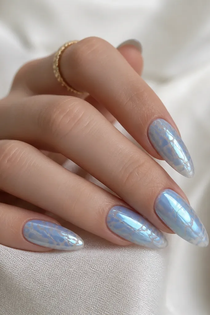 Almond nails with sky blue chrome in a marble pattern. Clear gel veins form a web-like map through the design, leaving thin transparent lines. The overall finish is glossy and mirror-like where the chrome sits.