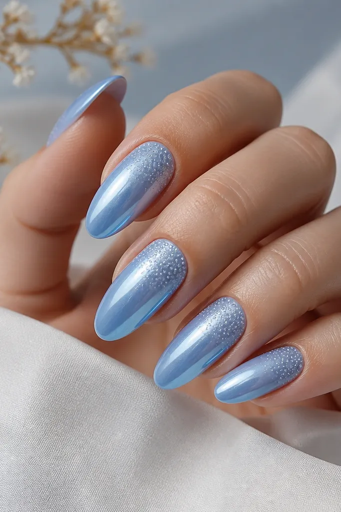 Long oval nails with sky blue chrome base. Near the cuticle, tiny pearlized micro dots fade outward toward the tips. Dots are subtle and glossy, not chunky.