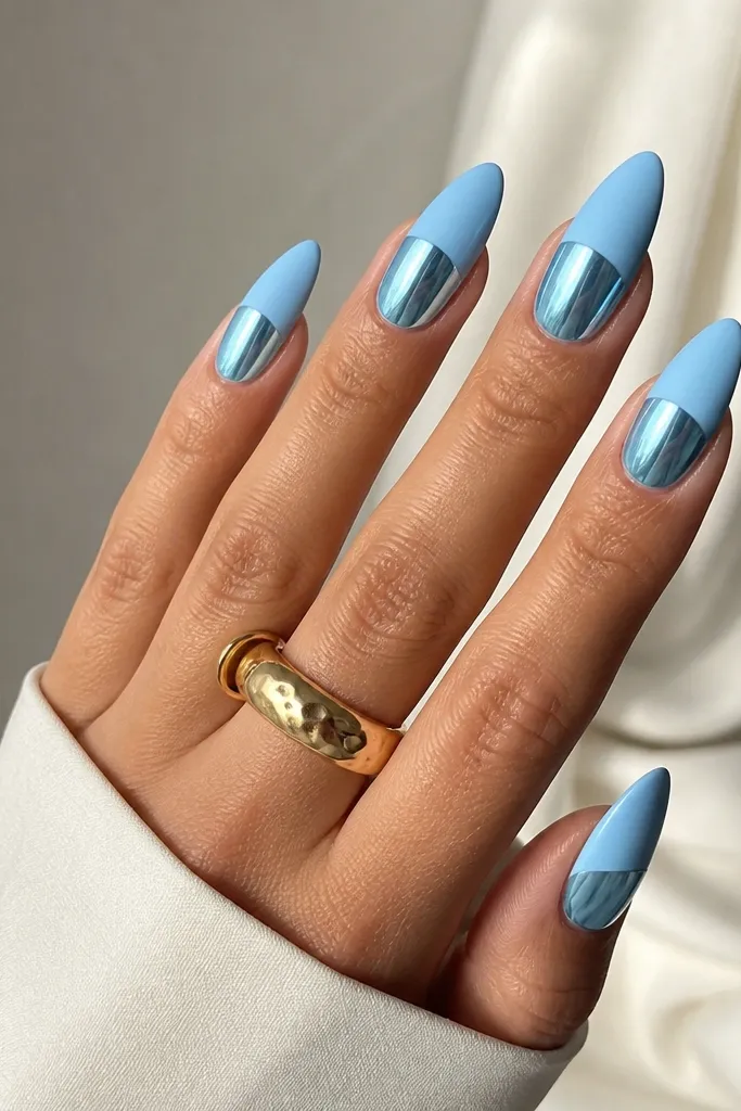 Long almond nails with sky blue chrome mirror on the bottom half. The top half is matte sky blue (no mirror), with a clean horizontal line. The bottom half still looks glossy and reflective.