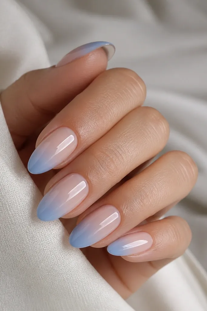 Square-to-short almond nails with a nude jelly base. The tips fade from sheer nude into a soft sky blue at the free edge, with a smooth airbrush-like gradient.