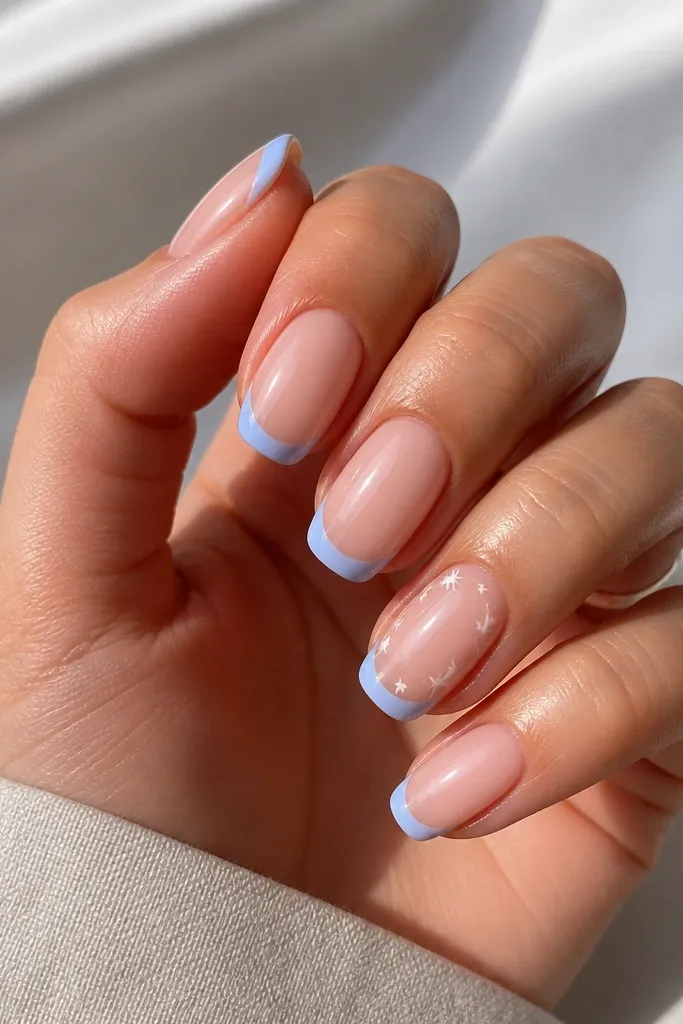A clean French tip in sky blue covers the nail's top edge while the rest is a sheer nude base. Small white stars are scattered near the sidewalls on two nails.