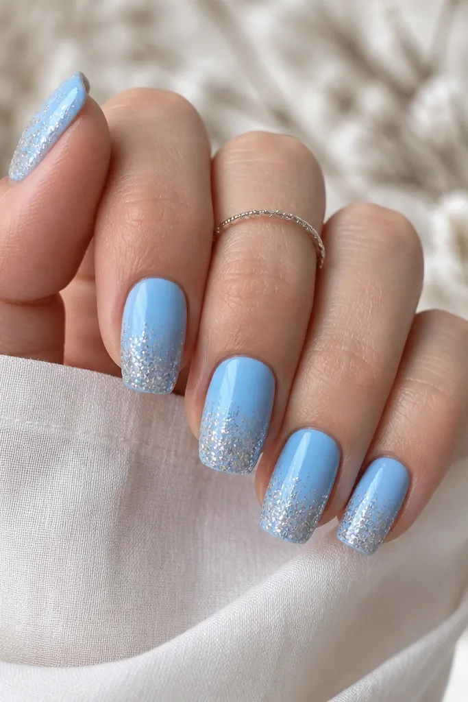 Nails start with solid sky blue at the base and turn into a glittery fade near the tips, with the densest glitter at the very edge.