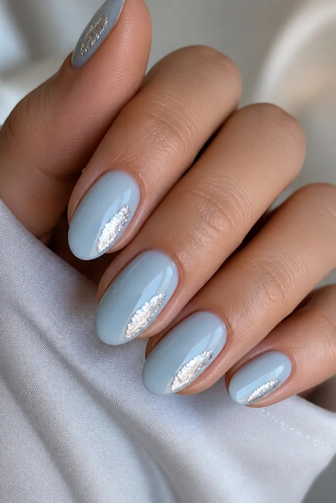 Glossy ice blue nails with a single irregular silver foil tear-drop shape placed near the side of the nail.