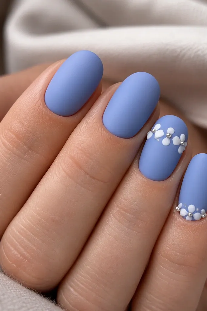 Matte periwinkle nails; two accent nails have small glossy white cloud-like dots clustered near the cuticle, with a tiny dot of silver chrome in the center.