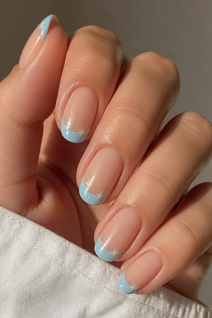 Nails with sky blue French tips and a few tiny star decals or hand-painted stars scattered near the center of the tip.