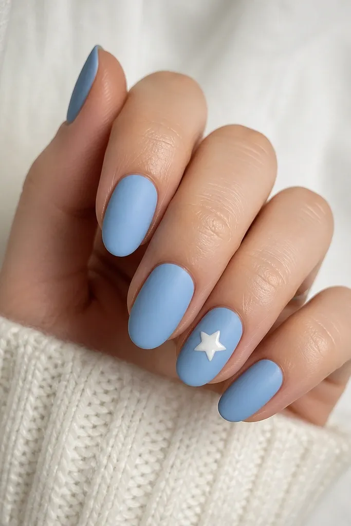 Most nails are matte sky blue, looking soft and powdery. On one nail, a small glossy white five-point star sits near the center, shining against the matte background.