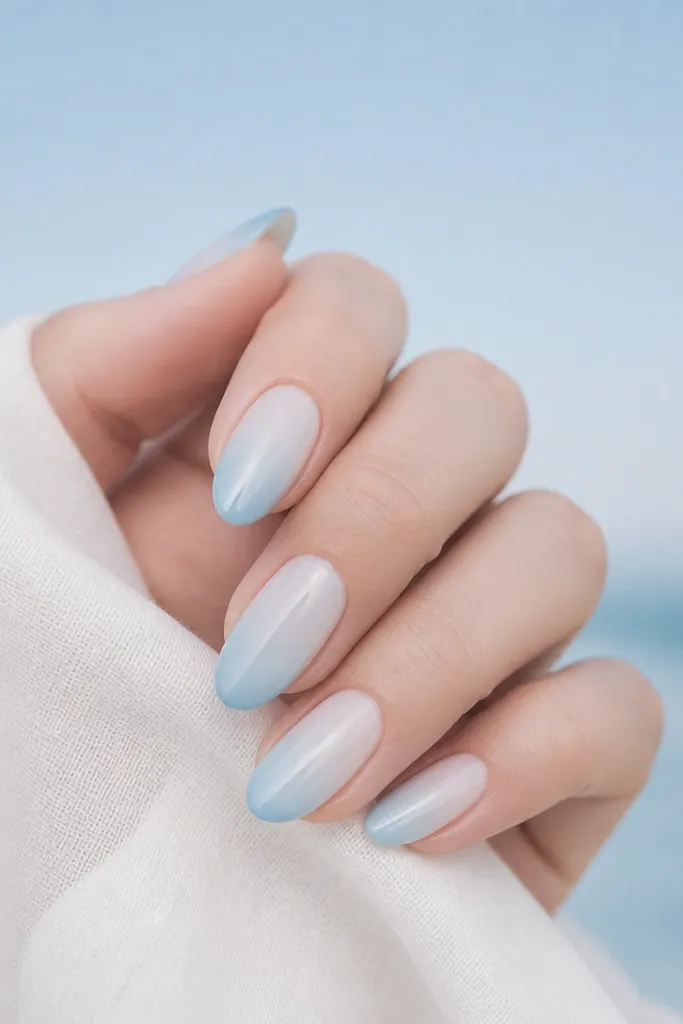 A soft gradient from sky blue at the tip fading into milky white near the cuticle. The nails are glossy and smooth with no harsh line.
