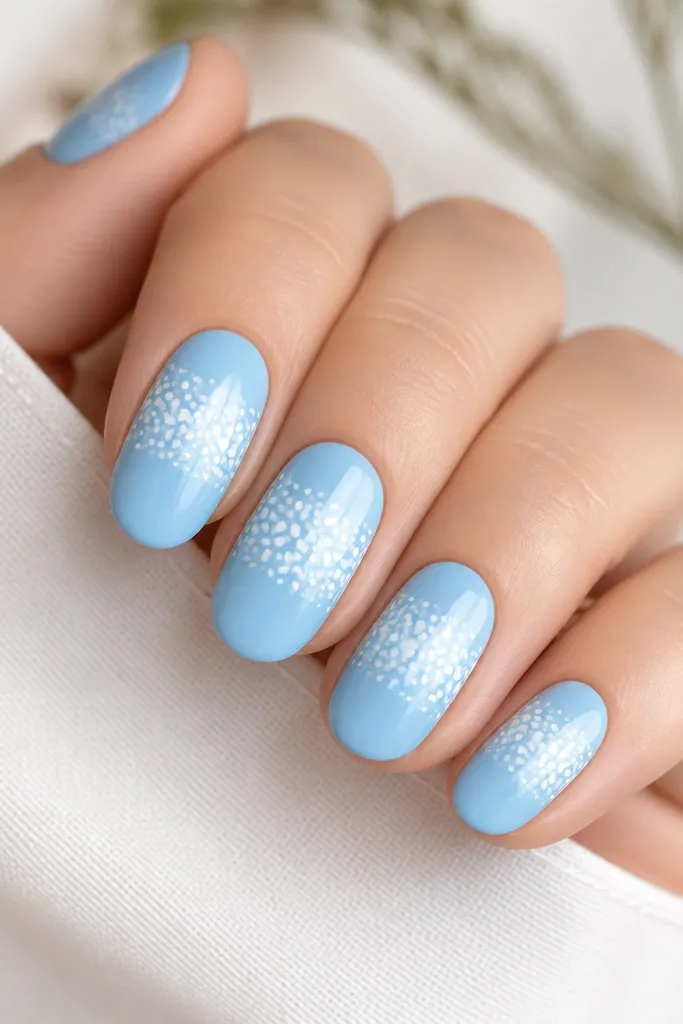 Sky blue nails with a white dotted pattern concentrated in a half-moon band across the middle. Dots vary slightly in size, and the rest of the nail is clean sky blue.