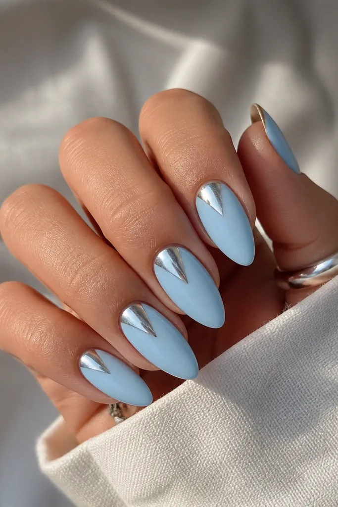 Sky blue nails with a silver chrome spear shape starting at the cuticle center and pointing toward the middle of the nail. The rest stays solid glossy sky blue.