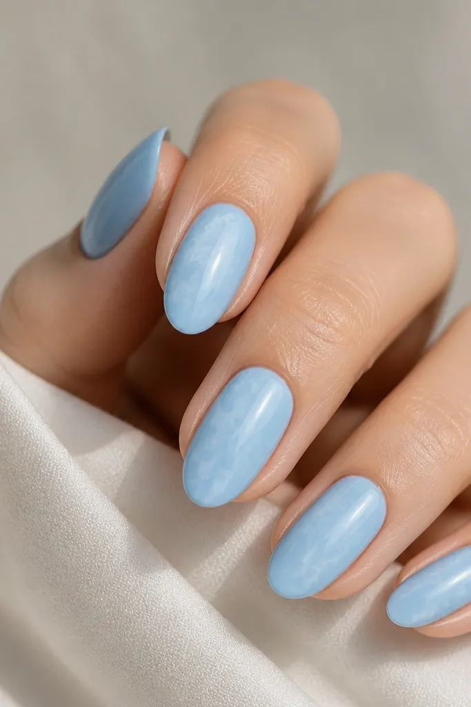 Sky blue nails with thin white and very light gray marble veins, mostly centered and delicate, glossy finish.