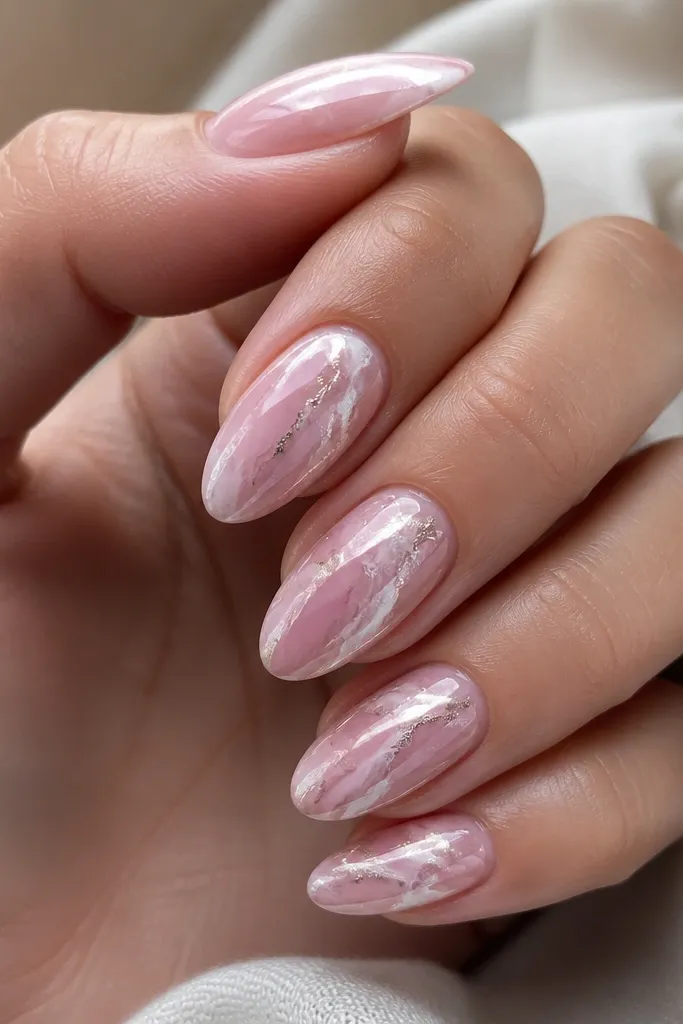 Soft pink nails with wispy white-pink marble lines. Chrome powder sits along the veins, creating bright reflective streaks like melted mirror metal.