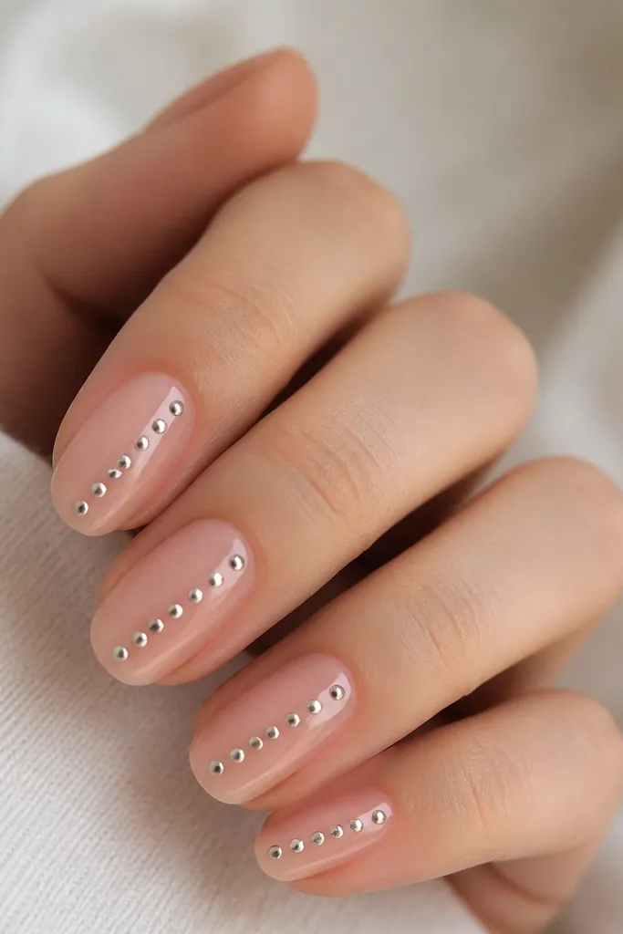 A translucent soft pink base. Along each nail, a diagonal row of small chrome dots runs from lower side to upper center. The dots are evenly spaced and reflective.
