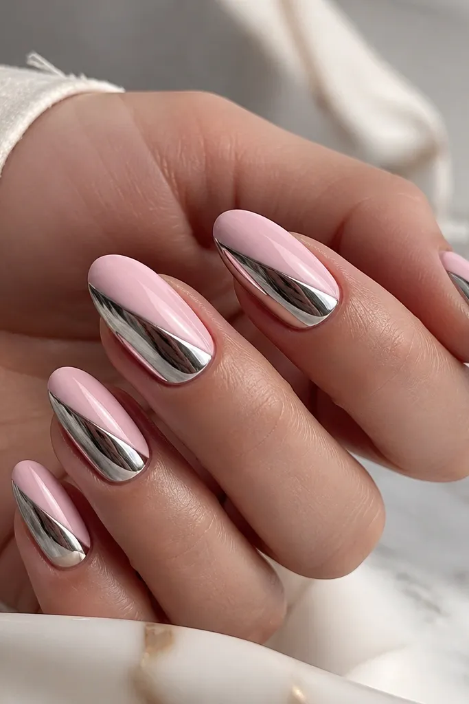 Two-tone nails: one side is soft pink glossy, the other side is mirror chrome. A sharp diagonal split creates a clean tuxedo look.