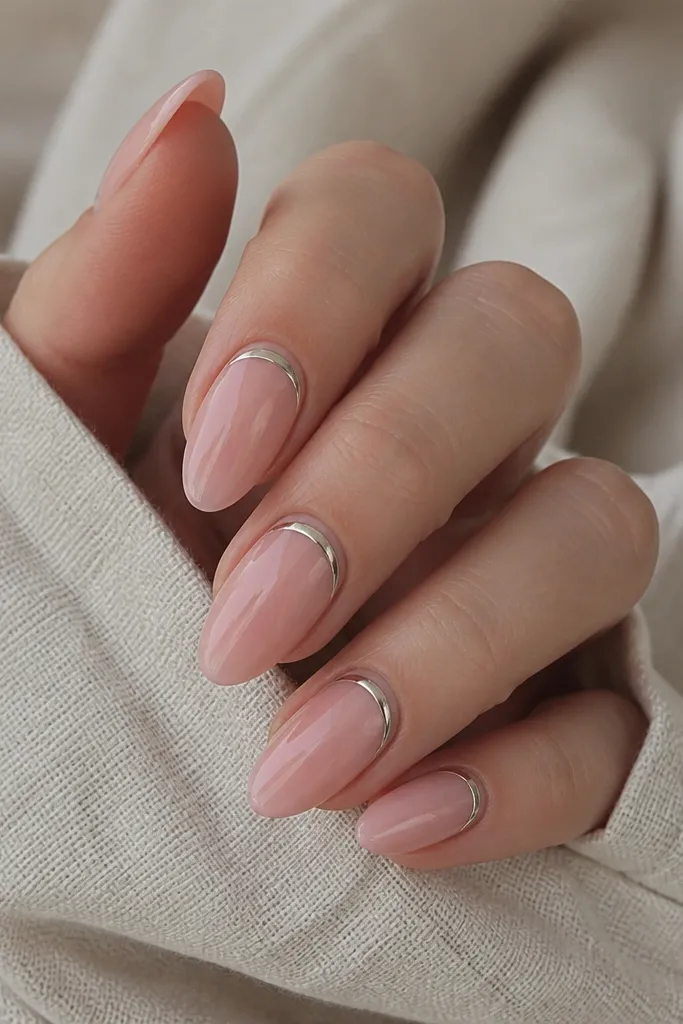 Nails with a clear cuticle area (negative space) and a sheer soft pink overlay. A chrome arch runs above the negative space, with the rest glossy and clean.